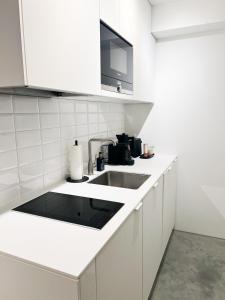 a white kitchen with a sink and a microwave at Suite One Einsteinstraße in Munich