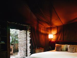 a bedroom with a bed with a red wall at Nomade Tulum in Tulum