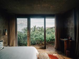 a bedroom with a bed and a large window at Nomade Tulum in Tulum
