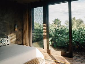 a bedroom with a bed and a large window at Nomade Tulum in Tulum