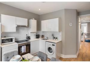 a kitchen with white cabinets and a dishwasher at Chic & Radiant Retreat in Harringay Ladder in London