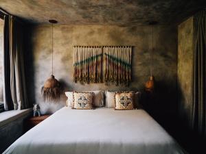 a bedroom with a large white bed with pillows at Nomade Tulum in Tulum