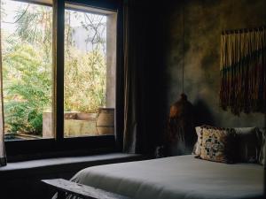 a bedroom with a bed and a large window at Nomade Tulum in Tulum