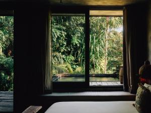 a bedroom with a window looking out into a forest at Nomade Tulum in Tulum