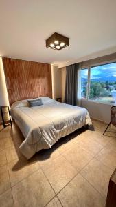 une chambre avec un grand lit et une grande fenêtre dans l'établissement Ginkgo Patagonia, à El Bolsón