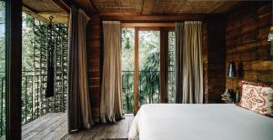 a bedroom with a bed and a large window at Nomade Tulum in Tulum