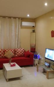 un salon avec un canapé rouge et une télévision dans l'établissement Angel Appartement, à Marrakech