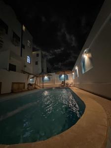 a swimming pool at night next to a building at Fnex House in Dahab