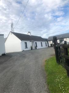 a white building with a fence in front of it at Cheerful 3 bedroom country farm house in Ennis