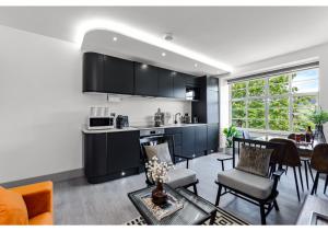een keuken met zwarte kasten en een woonkamer bij Modern Comforts 2 BD Flat - Sleeps 5 in Londen