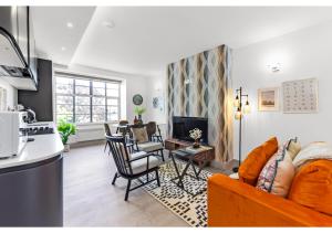 a living room with an orange couch and chairs at Modern Comforts 2 BD Flat - Sleeps 5 in London