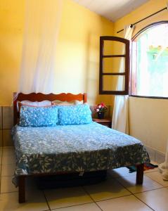 a bedroom with a bed with blue pillows and a window at Casa temporada Praia do Peró in Cabo Frio