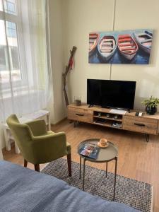 a living room with a tv and a chair and a table at OLD TISA Apartment in Senta
