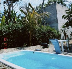 a swimming pool with a slide in a yard at Pousada Dona Carmem Ubatuba in Ubatuba