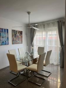 ein Esszimmer mit einem Glastisch und weißen Stühlen in der Unterkunft Apartamento Reyes La Carihuela in Torremolinos