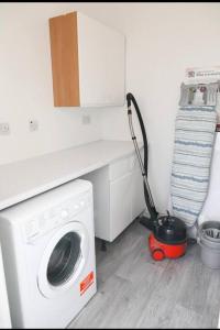 a washing machine in a kitchen with a vacuum at A hidden Gem in the heart of Dagenham! in Goodmayes
