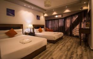 een hotelkamer met 2 bedden en een raam bij Nile Guardian Hotel in Caïro