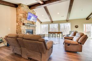 sala de estar con muebles de cuero y chimenea de piedra. en Roaring River Retreat with Home Gym and Fireplace!, 