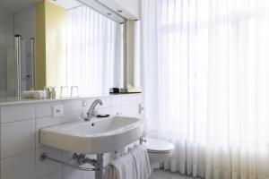 ein Badezimmer mit einem Waschbecken, einem WC und einem Spiegel in der Unterkunft Grand Hotel Beau Rivage Interlaken in Interlaken