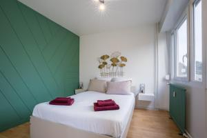 una camera da letto con un letto bianco e asciugamani rossi di Cosy, lumineux - 1ch'- 2 lits - 4pers'- Streaming a Metz