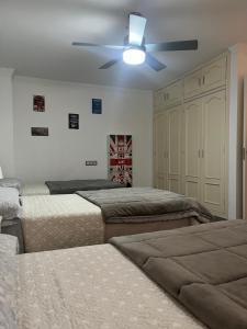 um quarto com 3 camas e uma ventoinha de tecto em Apartamento Reyes La Carihuela em Torremolinos