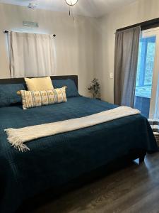 1 dormitorio con 1 cama con manta azul y ventana en Creed's Cottage at Four Oaks en New Braunfels
