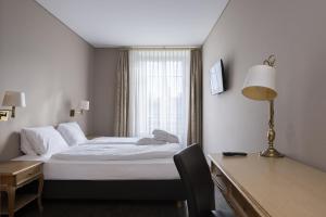 Pokój hotelowy z łóżkiem, biurkiem i oknem w obiekcie Grand Hotel Beau Rivage Interlaken w mieście Interlaken