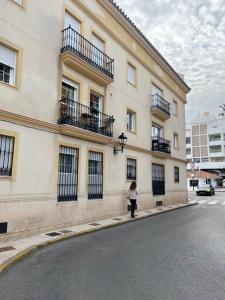 uma mulher a andar numa rua em frente a um edifício em Apartamento Reyes La Carihuela em Torremolinos