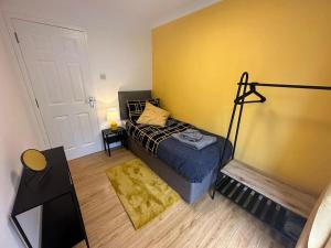 a bedroom with a bed and a yellow wall at Elegant room in stylish house in Milton Keynes