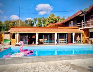 a swimming pool with a pink flamingo in front of a house at DOLINA SUNCA (Ranch Corral) in Popovača