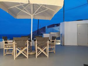 a patio with a table and chairs under an umbrella at Santorini Cave Suite in Éxo Goniá +24 photos