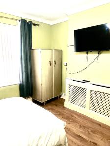 a bedroom with a bed and a television on a wall at PEACEFUL PLACE in Nottingham