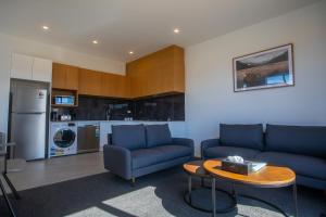 a living room with two blue couches and a table at Luminous Tekapo in Lake Tekapo