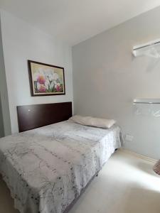een slaapkamer met een bed in een witte kamer bij Apartamento Aconchego na Praia da Costa in Vila Velha
