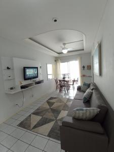 ein Wohnzimmer mit einem Sofa und einem TV in der Unterkunft Apartamento Aconchego na Praia da Costa in Vila Velha