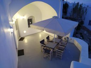 a group of chairs and a table with an umbrella at Santorini Cave Suite in Éxo Goniá