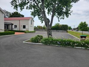 a parking lot with a tree and some flowers at Gateway Motor Inn in Masterton