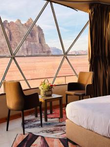 a room with a bed and chairs and a view of the desert at Rum Four Seasons luxury camp in Wadi Rum