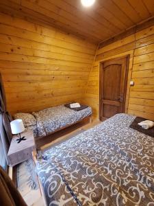 a bedroom with two beds in a wooden cabin at Brvnare Todorovic in Crni Vrh