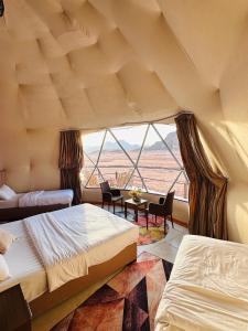 a room with two beds and a large window at Rum Four Seasons luxury camp in Wadi Rum