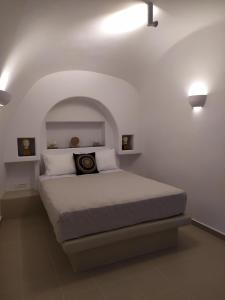 a bedroom with a bed in a white room at Santorini Cave Suite in Éxo Goniá
