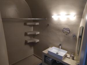 a bathroom with a white sink and a mirror at Santorini Cave Suite in Éxo Goniá