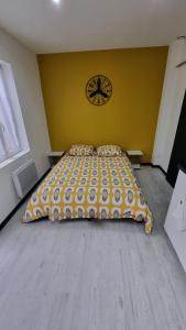 - un grand lit dans une chambre dotée d'un mur jaune dans l'établissement Studio Jasmin avec jardin, rénové, à Saint-Quentin