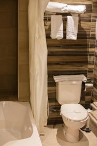 een badkamer met een toilet, een bad en handdoeken bij Nile Guardian Hotel in Caïro