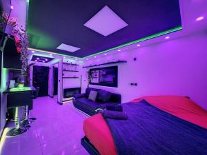 a purple room with a bed and a couch at C12 Deluxe in Cap d'Agde