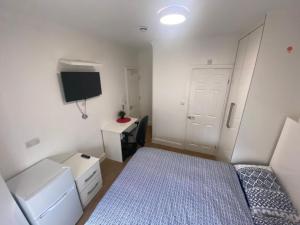 a small bedroom with a bed and a tv at THE ROYAL BOUTIQUE TRAFALGAR LODGE BY LONDON HEATHROW UK, PRIVATE HOME OFFER's FREE PARKING, WIFI , KITCHEN, GARDEN & LAUNDRY SERVICES, SLEEP 10 in Northolt