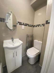 a bathroom with a toilet and a sink and a mirror at THE ROYAL BOUTIQUE TRAFALGAR LODGE BY LONDON HEATHROW UK, PRIVATE HOME OFFER's FREE PARKING, WIFI , KITCHEN, GARDEN & LAUNDRY SERVICES, SLEEP 10 in Northolt