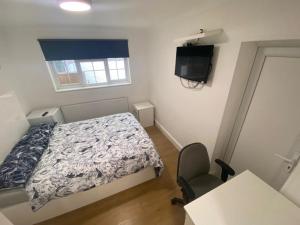 a small bedroom with a bed and a television at THE ROYAL BOUTIQUE TRAFALGAR LODGE BY LONDON HEATHROW UK, PRIVATE HOME OFFER's FREE PARKING, WIFI , KITCHEN, GARDEN & LAUNDRY SERVICES, SLEEP 10 in Northolt