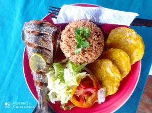 a pink plate of food with bread and vegetables at HOSTAL BELLEZA TROPICAL in Moñitos