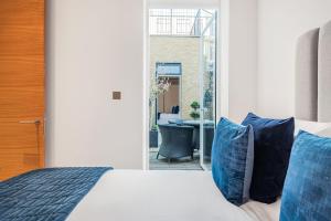 a bedroom with a bed with blue pillows and a desk at ARCORE Premium Apartments Oxford Street Area in London